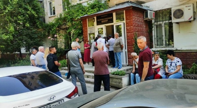 Люди стоят в очереди в «Крымэнерго» прямо на улице в жару. Фото Вадима ЗАРИЦКОГО.