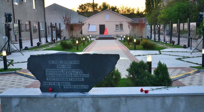 Мемориал окружён забором из колючей проволоки с опорами из рельсов в знак того, что «Картофельный городок» был пересыльным лагерем.